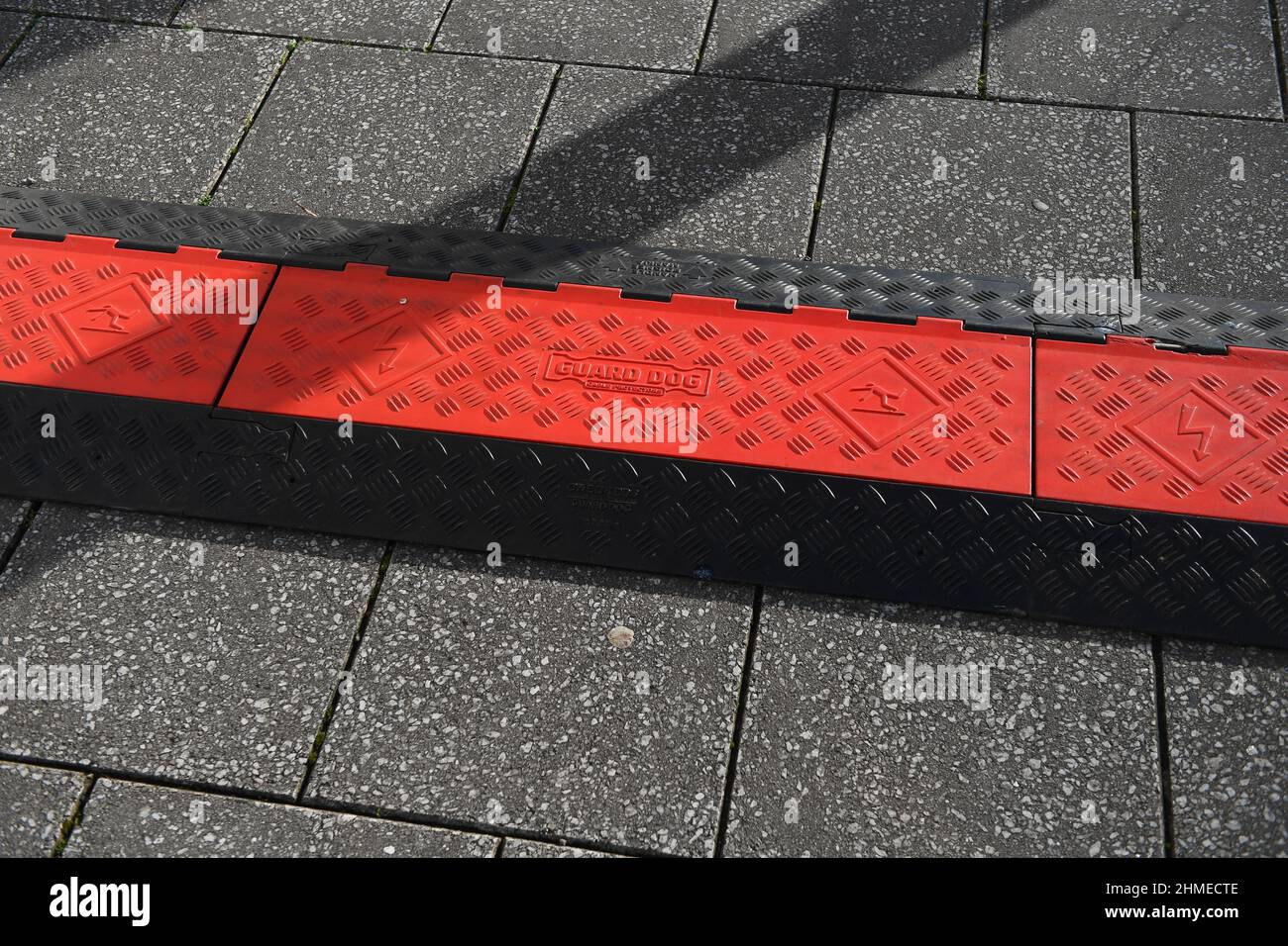 Schutz vor Kabelschutzsystem für Hunde, das bei einem Ereignis auf dem Bürgersteig verlegt wird, um Stolpergefahren und elektrische Sicherheit zu verhindern. Stockfoto