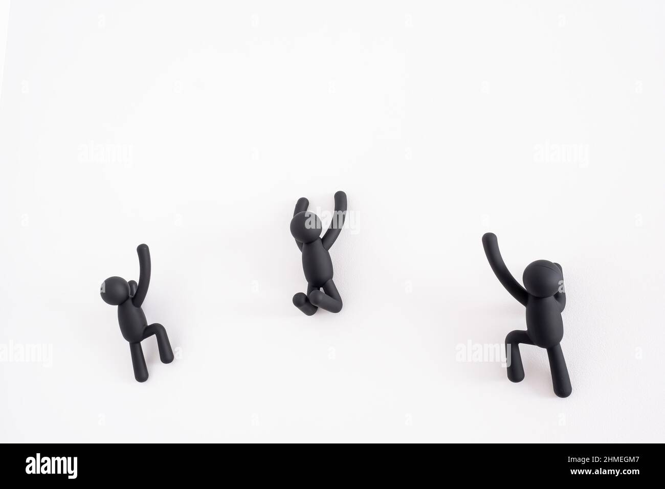 3 schwarze 3D Marionetten, die über einen weißen Hintergrund klettern, menschlicher Charakter, Person, die an einer weißen Wand hängt, Konzept der Selbstverbesserung, helfen sich gegenseitig Stockfoto