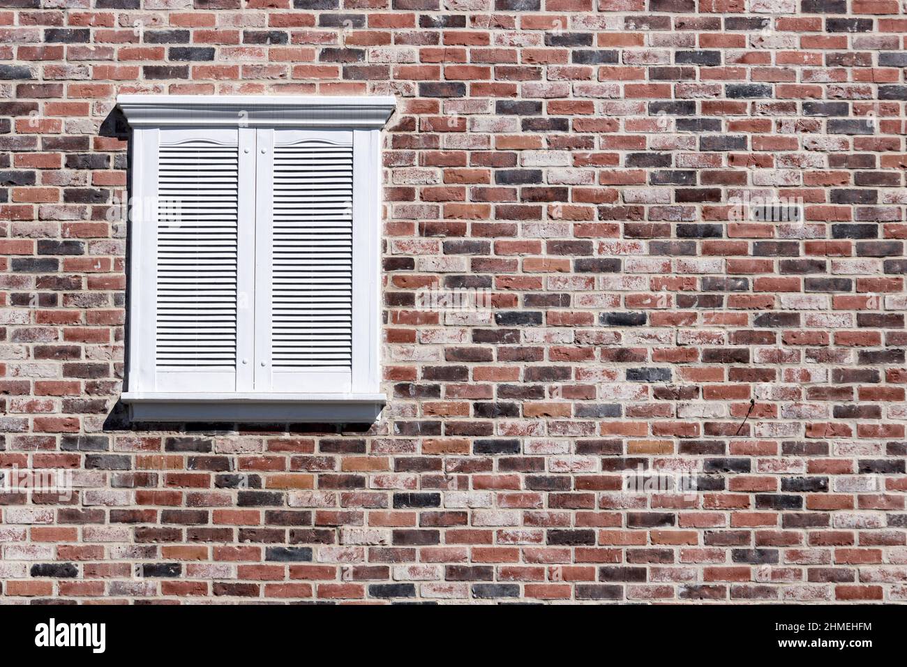 Rote Backsteine und weiße rechteckige Fenster mit Fenstereinfassung Stockfoto