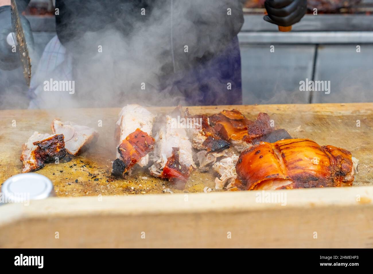Straßengrill, gebratenes Fleisch. Ein Mann schneidet ein gebratenes Stück Fleisch in Portionen. Traditionelle weihnachtsmarkt in Monaco. Hochwertige Fotos Stockfoto