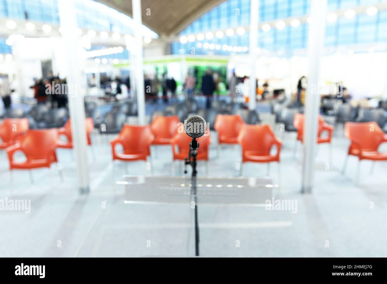 Mikrofon im Fokus, leere Stühle ohne Personen im Konferenzraum im Hintergrund Stockfoto