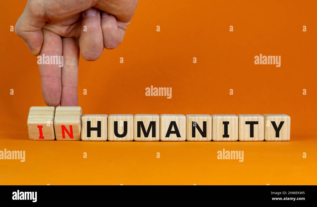Symbol für Menschlichkeit oder Unmenschlichkeit. Geschäftsmann dreht Holzwürfel ändert das Wort Unmenschlichkeit zur Menschheit. Schöne orange Tabelle orange Hintergrund, Kopie Stockfoto