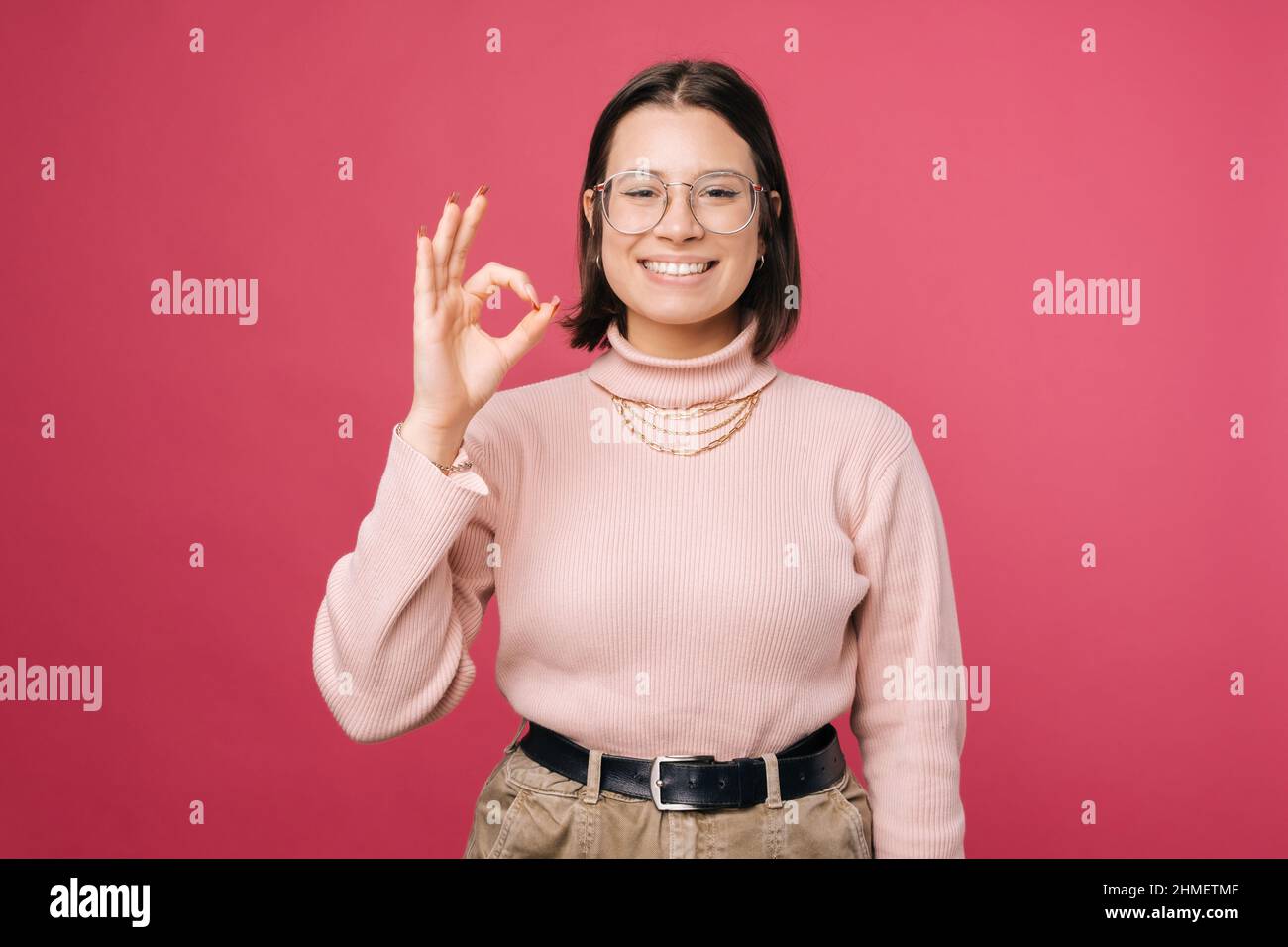 Alles wird in Ordnung sein, sagt eine junge Frau, die eine gute Geste zeigt. Porträt auf rosa Hintergrund. Stockfoto