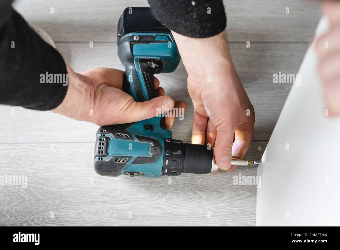 Ein unbekannter Mann kaukasischen männlichen mit elektrischen Akku-Schraubendreher Bohrer Montage Möbel zu Hause DIY Schreiner bei der Arbeit in der Nähe auf Händen kopieren Spa Stockfoto