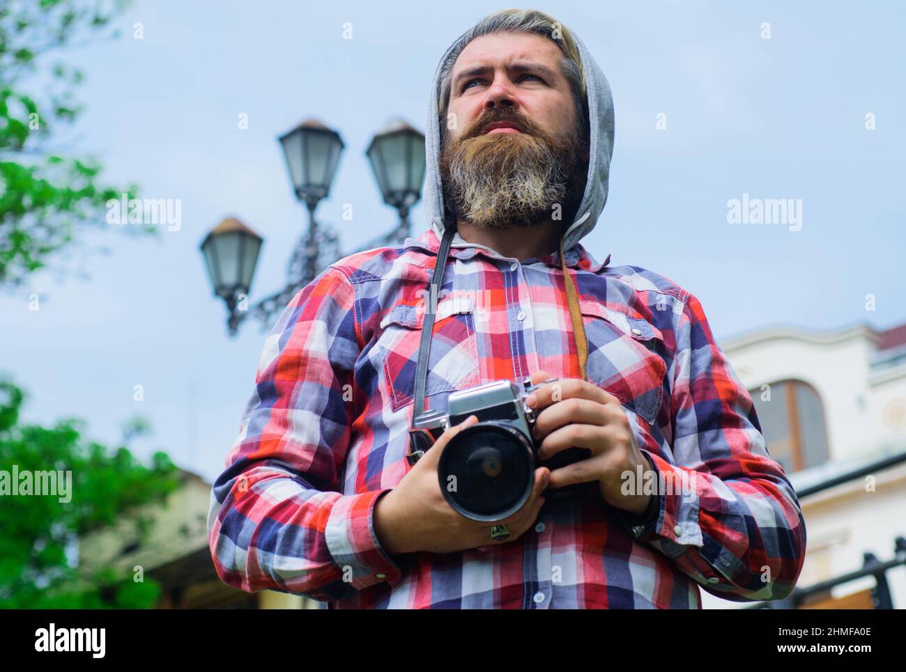 Fotograf mit Fotokamera. Bärtiger Mann, der Foto auf einer Digitalkamera macht. Reisende machen Fotos auf der Straße. Stockfoto