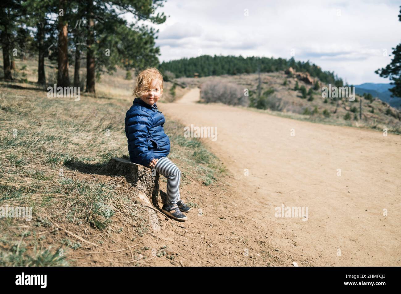 Fröhliches Mädchen, das auf einem Pfad in Colorado sitzt Stockfoto