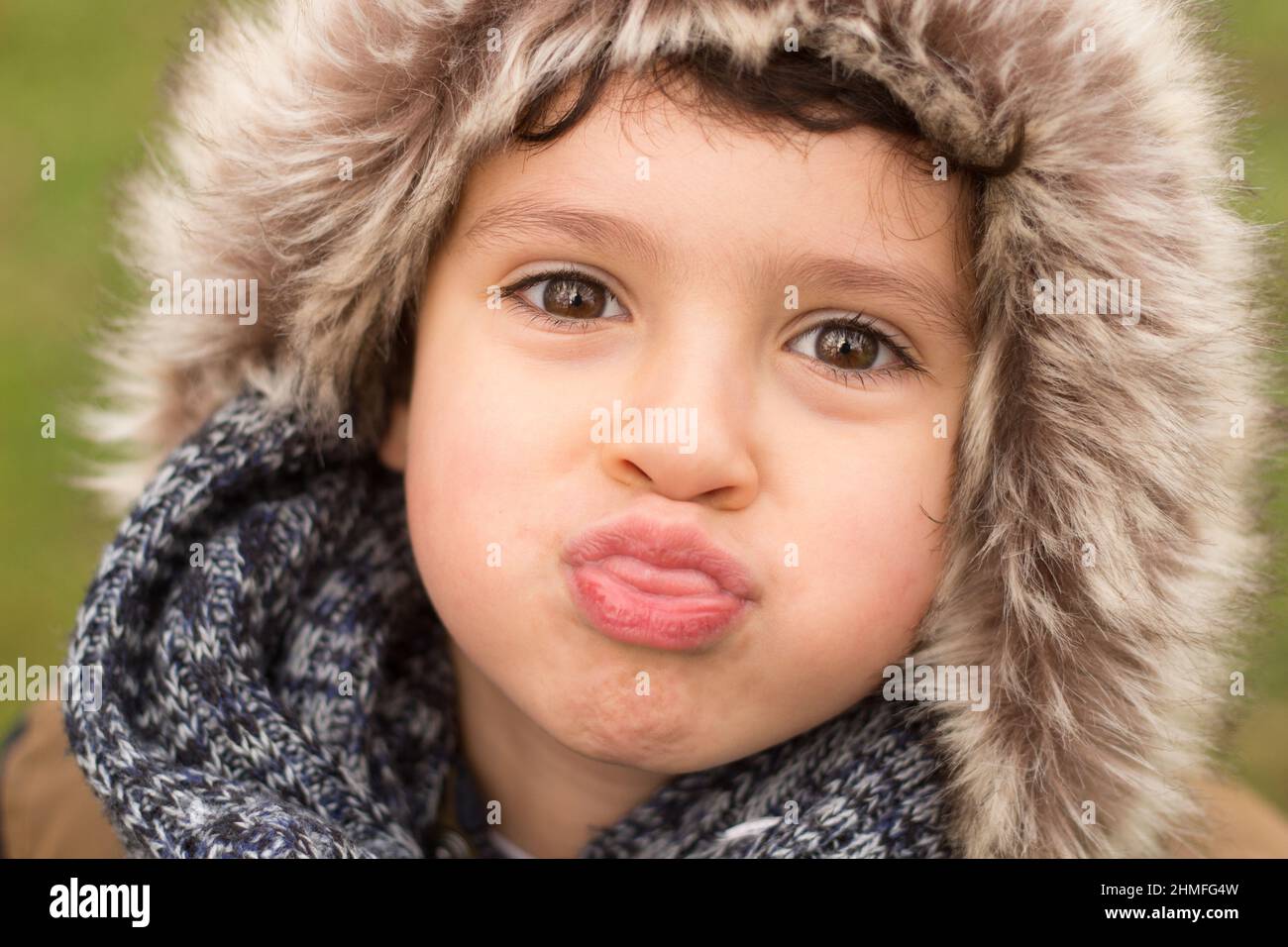 Ein kleines Kind, das die Zunge herausstreckt und Gesichter dumm glücklich und verspielt macht Stockfoto