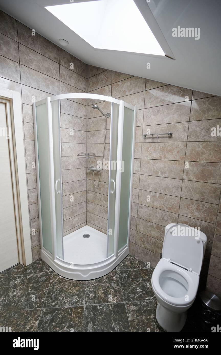 Sauberes Badezimmer mit Dusche und Toilette in braun gefliesten Wänden Stockfoto
