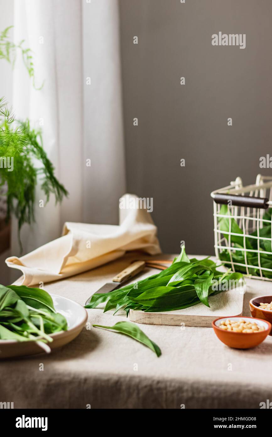 Frisch gepflückter Bärlauch, Ramson in einem weißen Metallkorb auf dem Tisch mit Leinentischtuch. Frühlingskräuter. Vegane Küche. Sauberes Essen. Saisonal Stockfoto