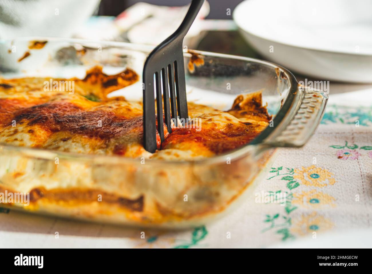 Cannelloni mit Spinat Nahaufnahme, Tomatensauce, Bachamel und Käse auf Tischtuch mit Gabel Einnahme Portion . Traditionelle hausgemachte klassische italienische cui Stockfoto