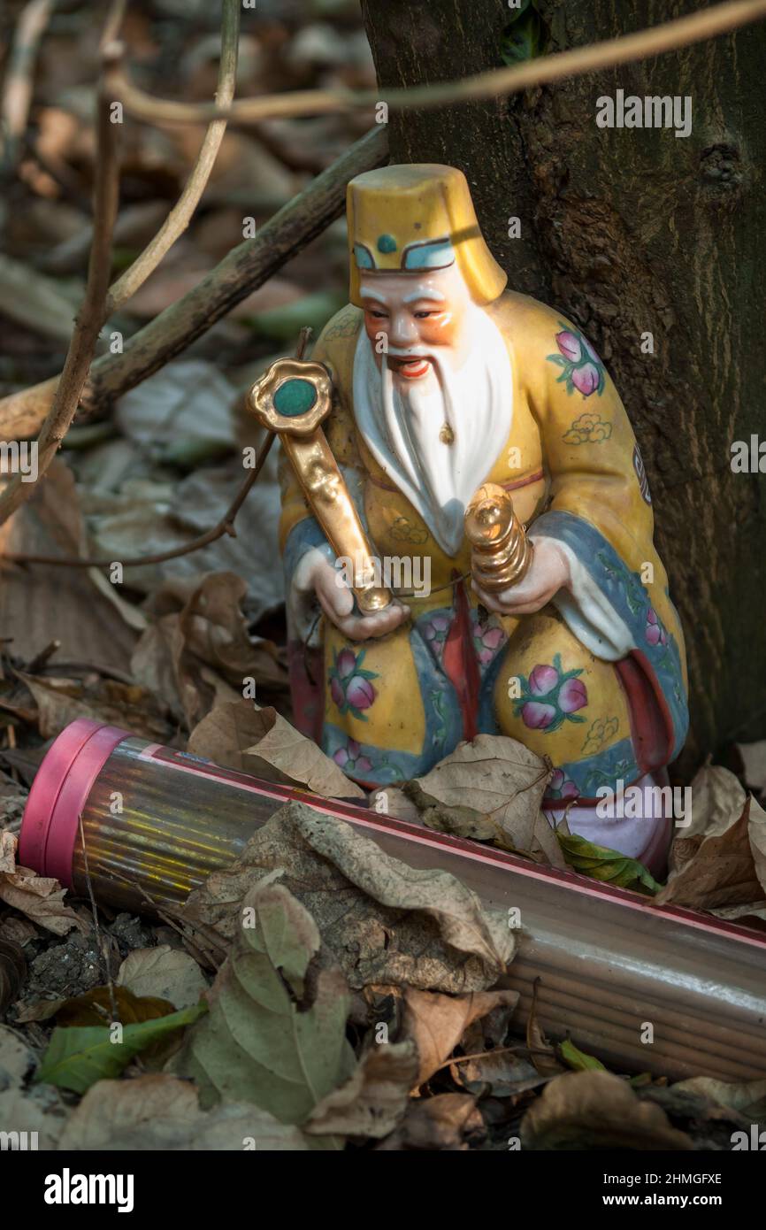 Eine Figur von TU Di Gong (土地公 'Herr des Bodens und des Bodens') verließ das Haus in der Nähe eines zerstörten und überwucherten Hauses, Nim Shue Wan, Lantau Island, Hongkong Stockfoto