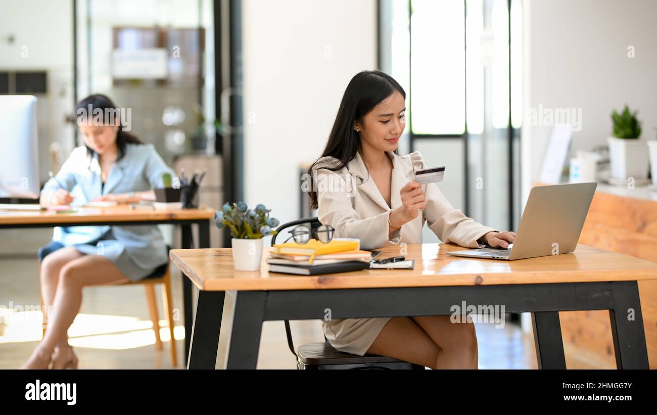 Attraktive asiatische weibliche Offizier mit Laptop und halten eine Kreditkarte. Online-Zahlung, Einkaufen. Stockfoto