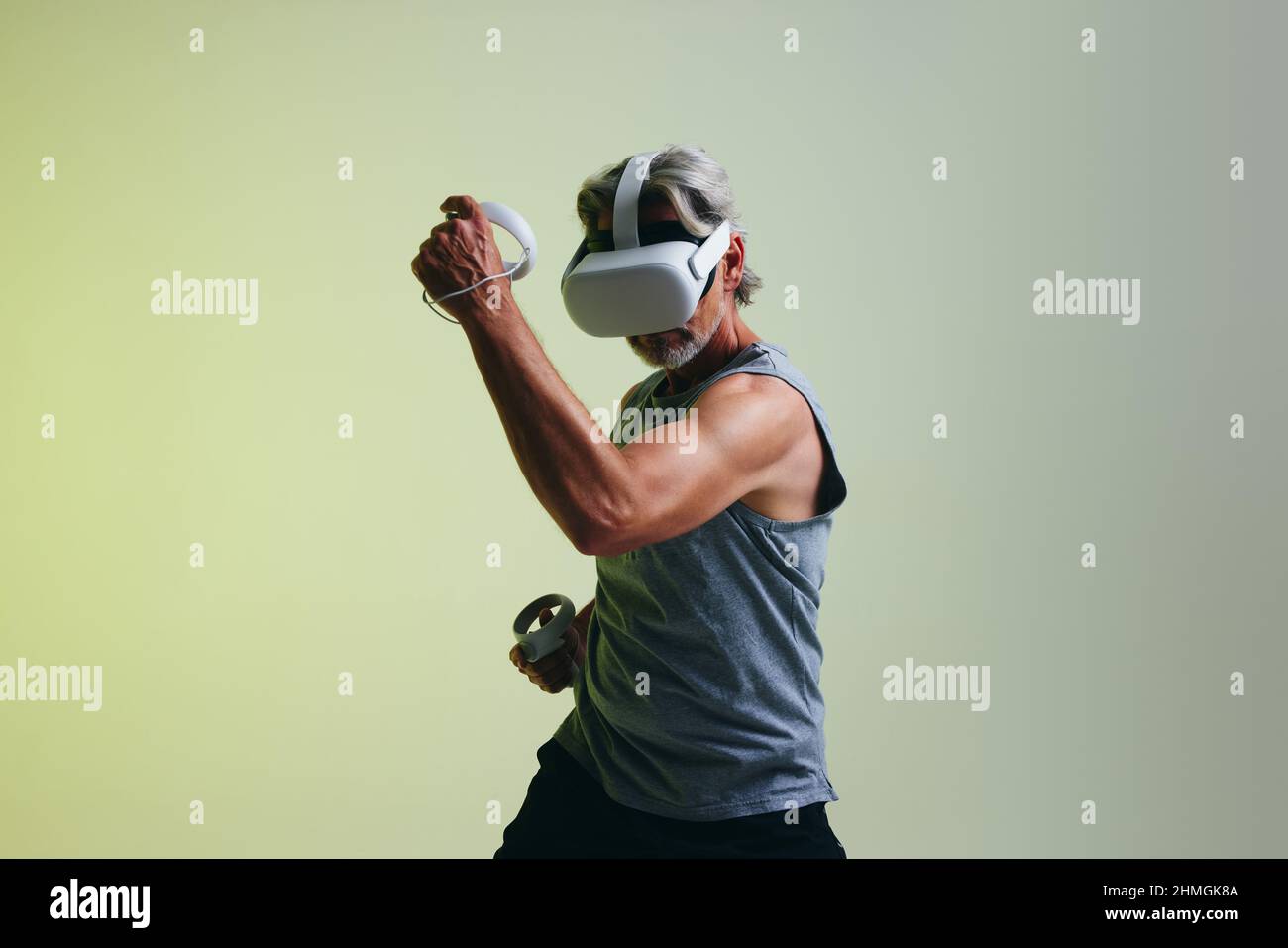 Reifer Mann, der Spiele spielt, während er ein Virtual-Reality-Headset trägt. Mann genießt eine 3D Simulation, während er vor einem Studiohintergrund steht. Stockfoto