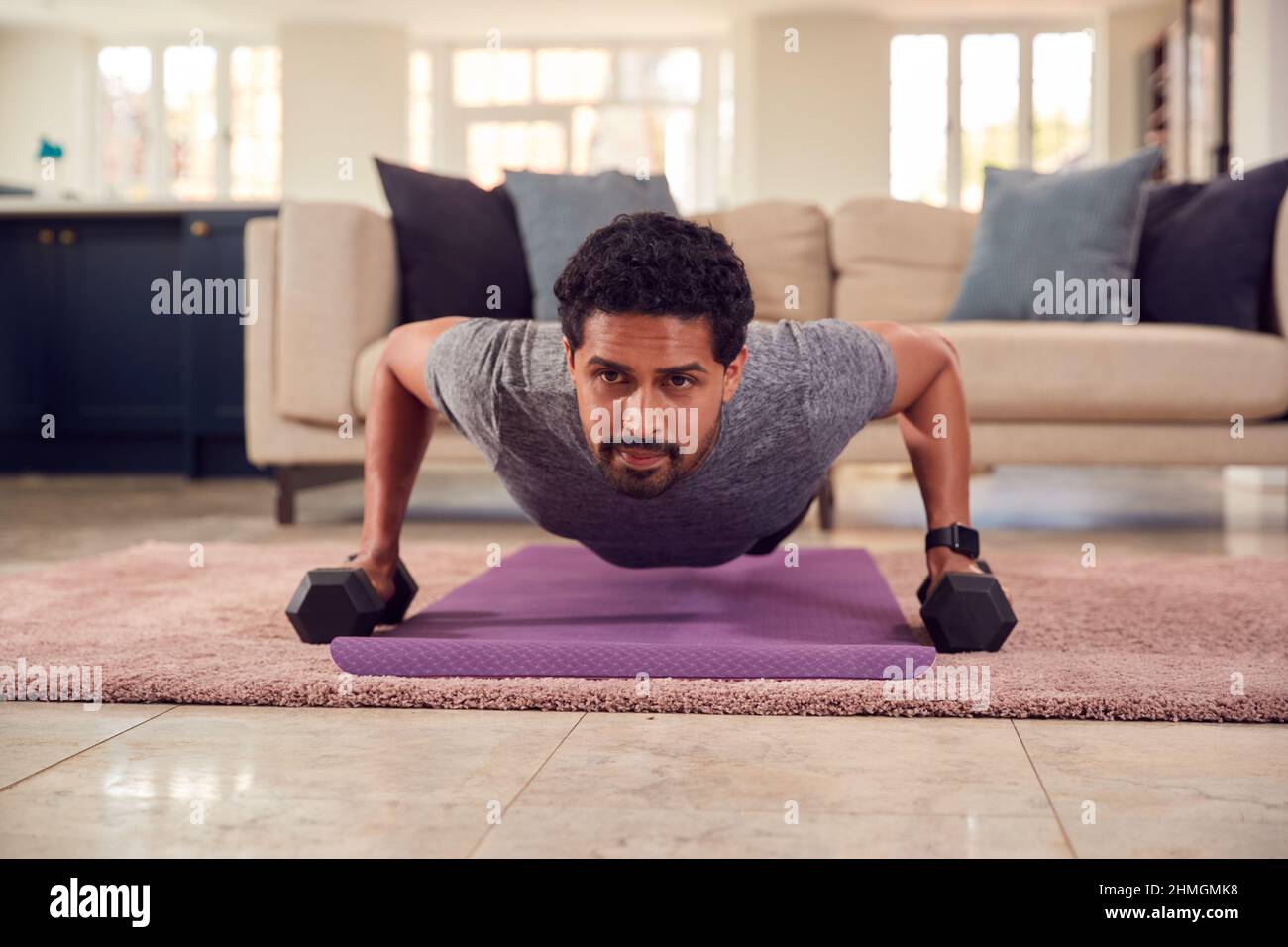 Mann In Fitness-Kleidung Zu Hause In Der Lounge Mit Handgewichten Trainieren Stockfoto