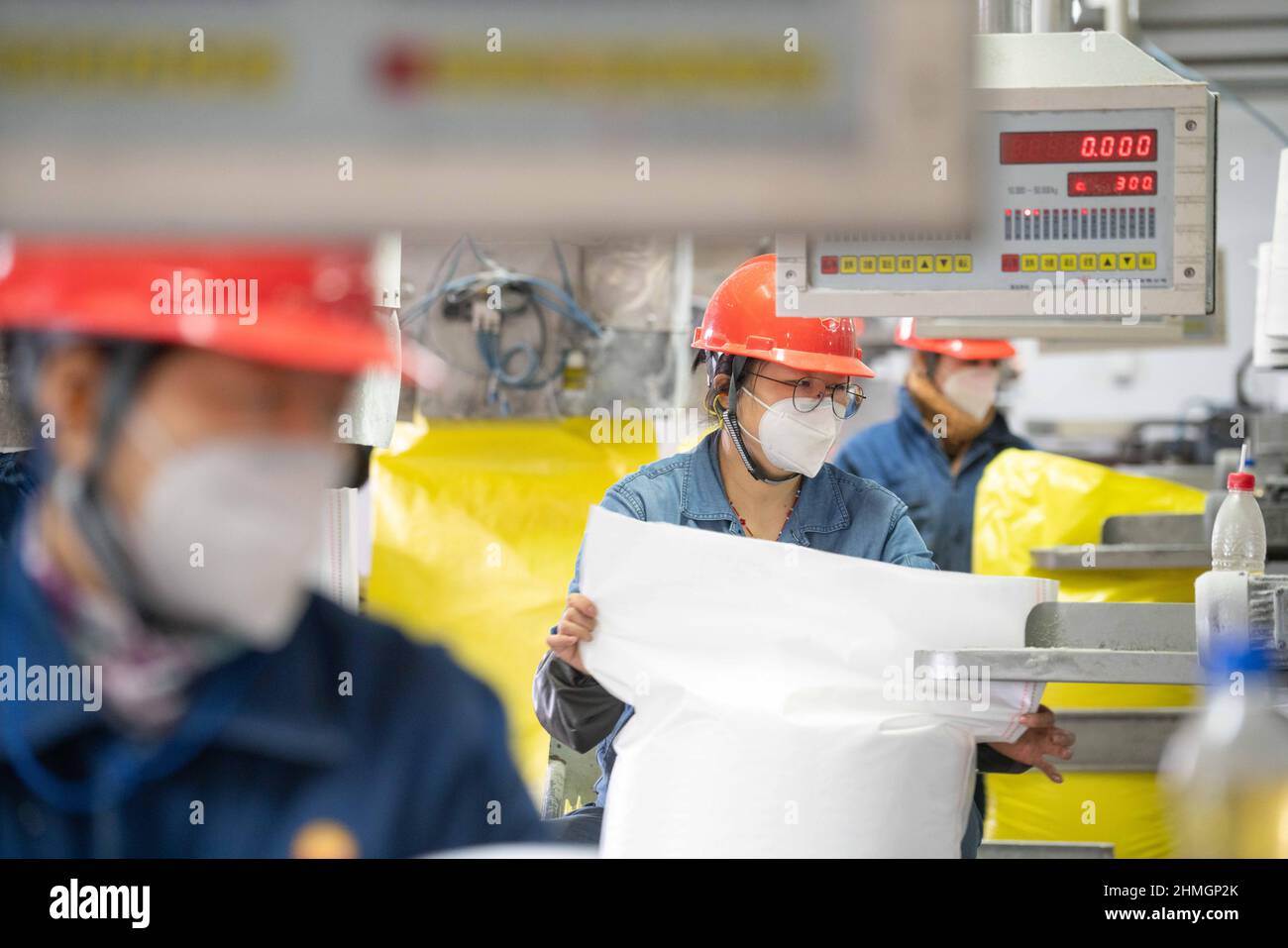 BAZHOU, CHINA - 10. FEBRUAR 2022 - Arbeiter verkapseln Dünger in der Fertigproduktverpackungswerkstatt der sinopec Niederlassung in Bozhou, Xinjiang PR Stockfoto