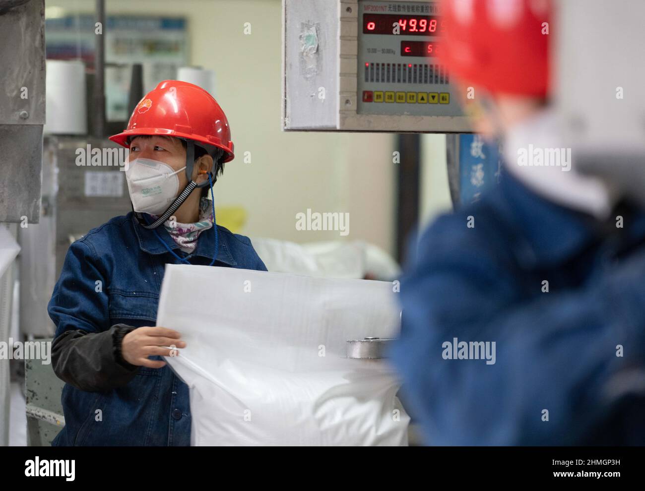 BAZHOU, CHINA - 10. FEBRUAR 2022 - Arbeiter verkapseln Dünger in der Fertigproduktverpackungswerkstatt der sinopec Niederlassung in Bozhou, Xinjiang PR Stockfoto
