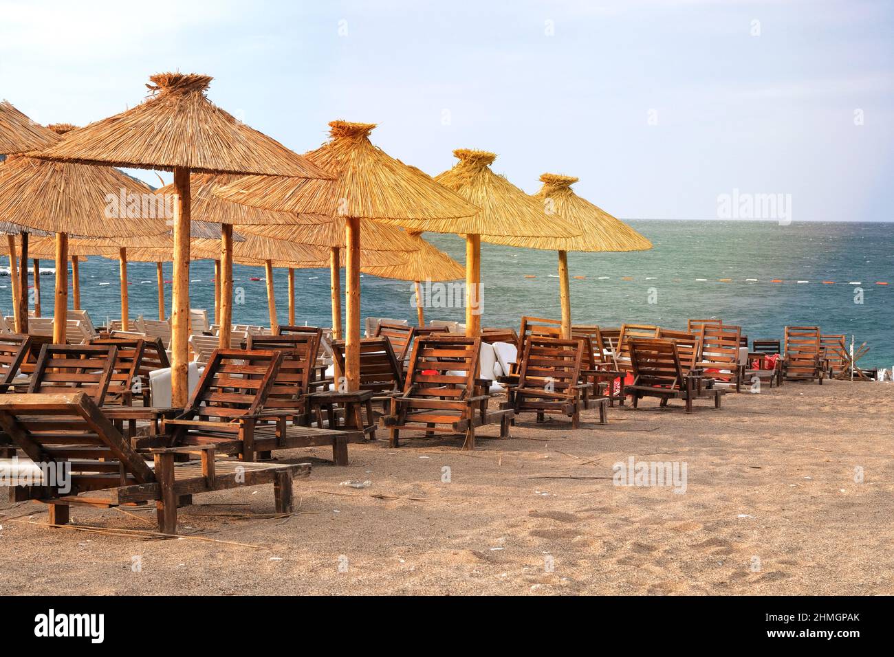 Strohschirme auf tropischem, idyllischem Resort. Blaues Meer und Himmel mit sanftgelbem Sonnenlicht. Stockfoto