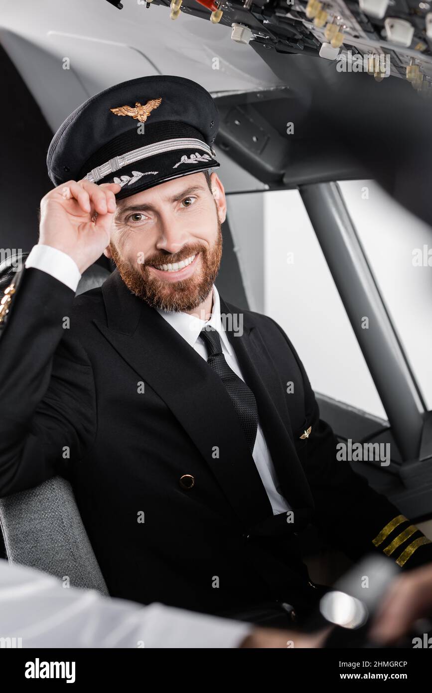 Bärtiger Pilot mit einheitlicher Verstellkappe und lächelndem, fast verschwommenem Co-Pilot Stockfoto