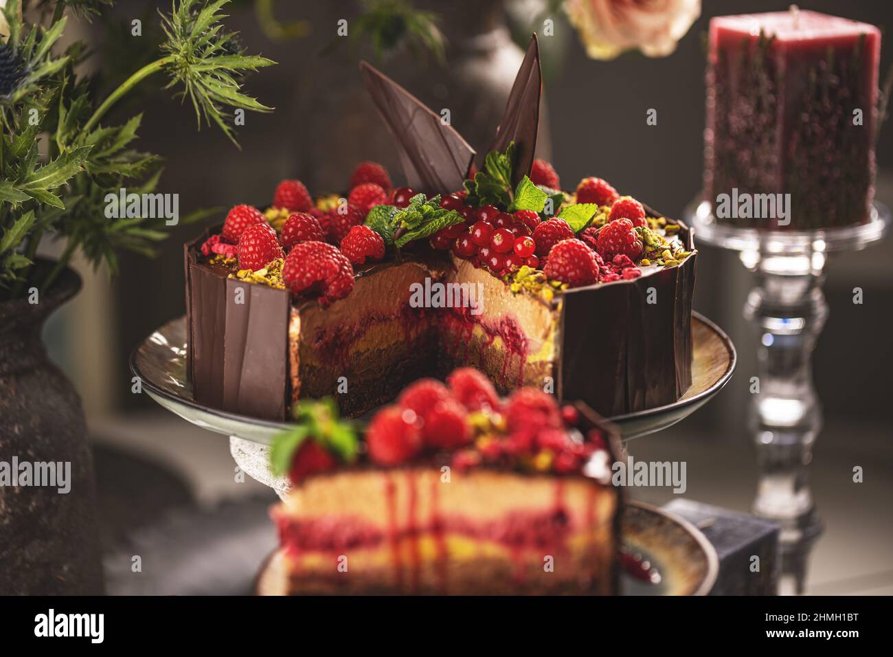 Stillleben von leckeren geschichteten Mousse Kuchen mit geschmolzener Schokolade Belag mit Himbeeren verziert Stockfoto
