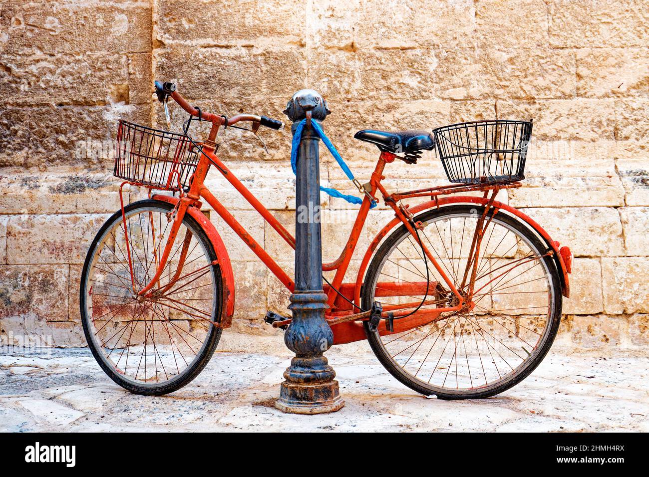 Ein rotes Fahrrad lehnt sich an eine Metallsäule Stockfoto