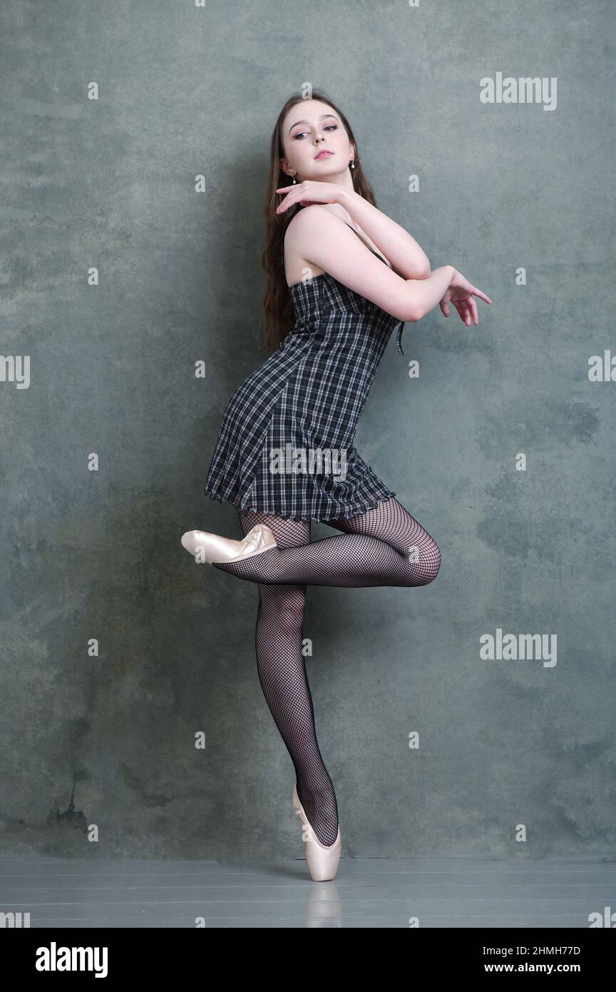 Ballerina in kariertem Kleid und Fischernetze in Ballettpose Stockfoto