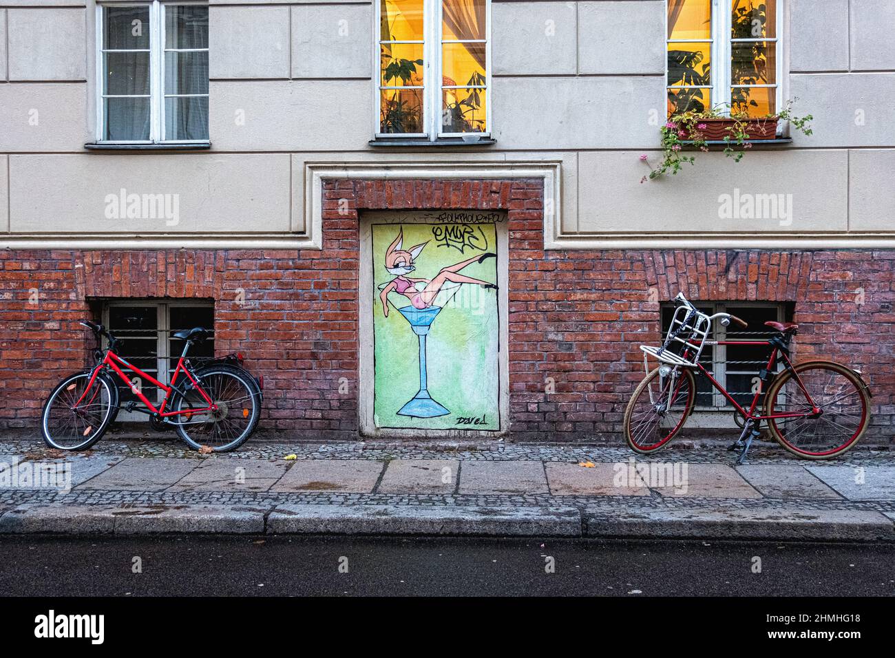 Blick auf die Mulackstrasse, Mitte, Berlin. Appartementgebäude, geparkte Fahrräder, gepflasterter Bürgersteig und gewagte Street Art Paste-up Stockfoto