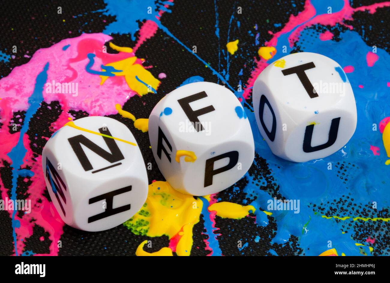 NFT in Buchstabenwürfeln mit Farbspritzern in mehreren Farben Stockfoto