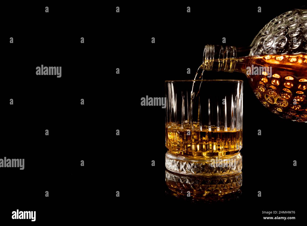 Gießen Glas Whisky auf schwarzem Hintergrund Stockfoto
