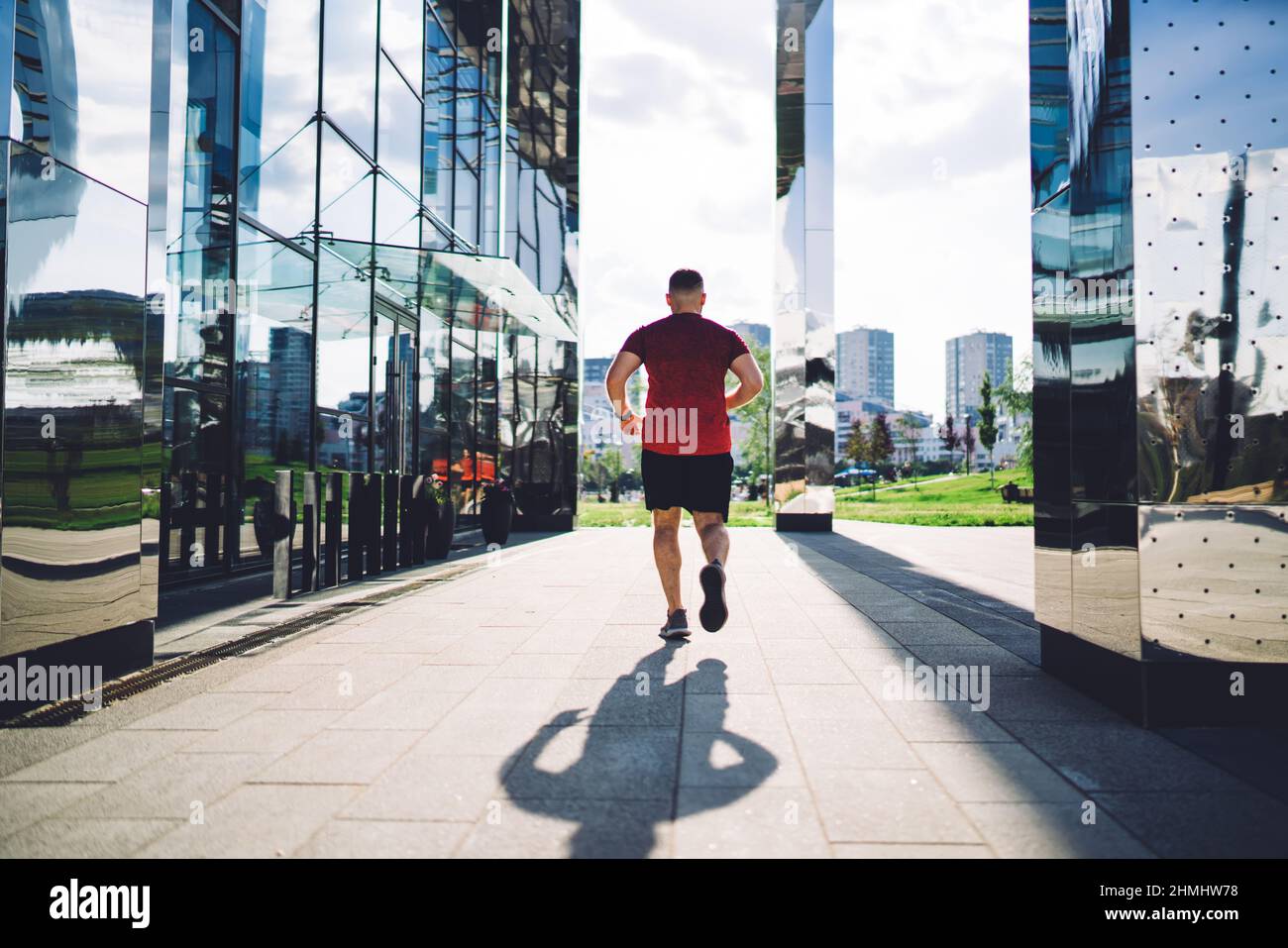 Gesichtsloser Sportler, der zwischen Glasgebäuden joggt Stockfoto