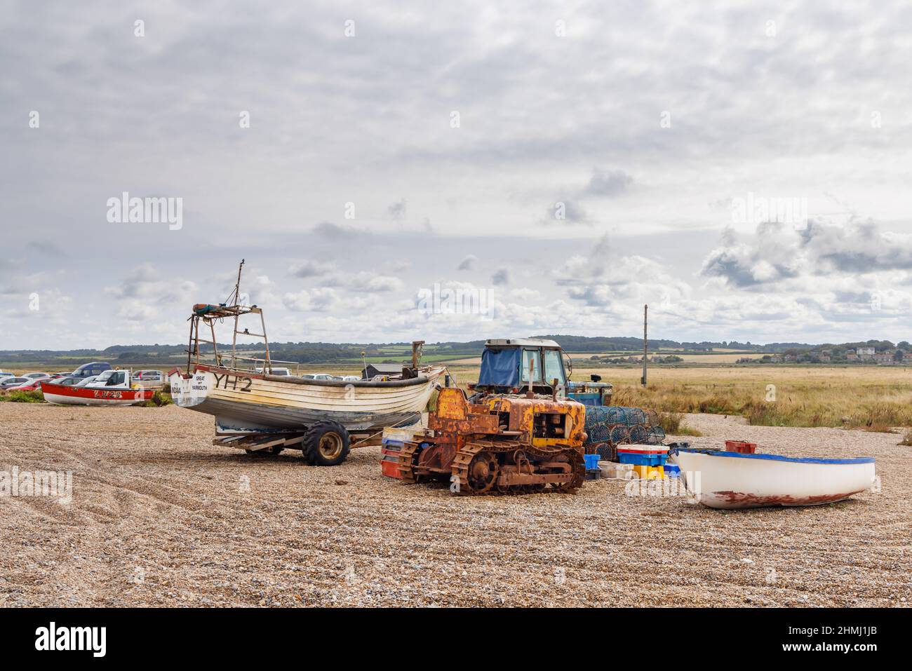 Ein rostiger alter Raupendozer, ein Traktor und ein Fischerboot auf einem Kiesstrand, Cley-Next-the-Sea, einem Dorf im Norden von Norfolk, East Anglia, England Stockfoto
