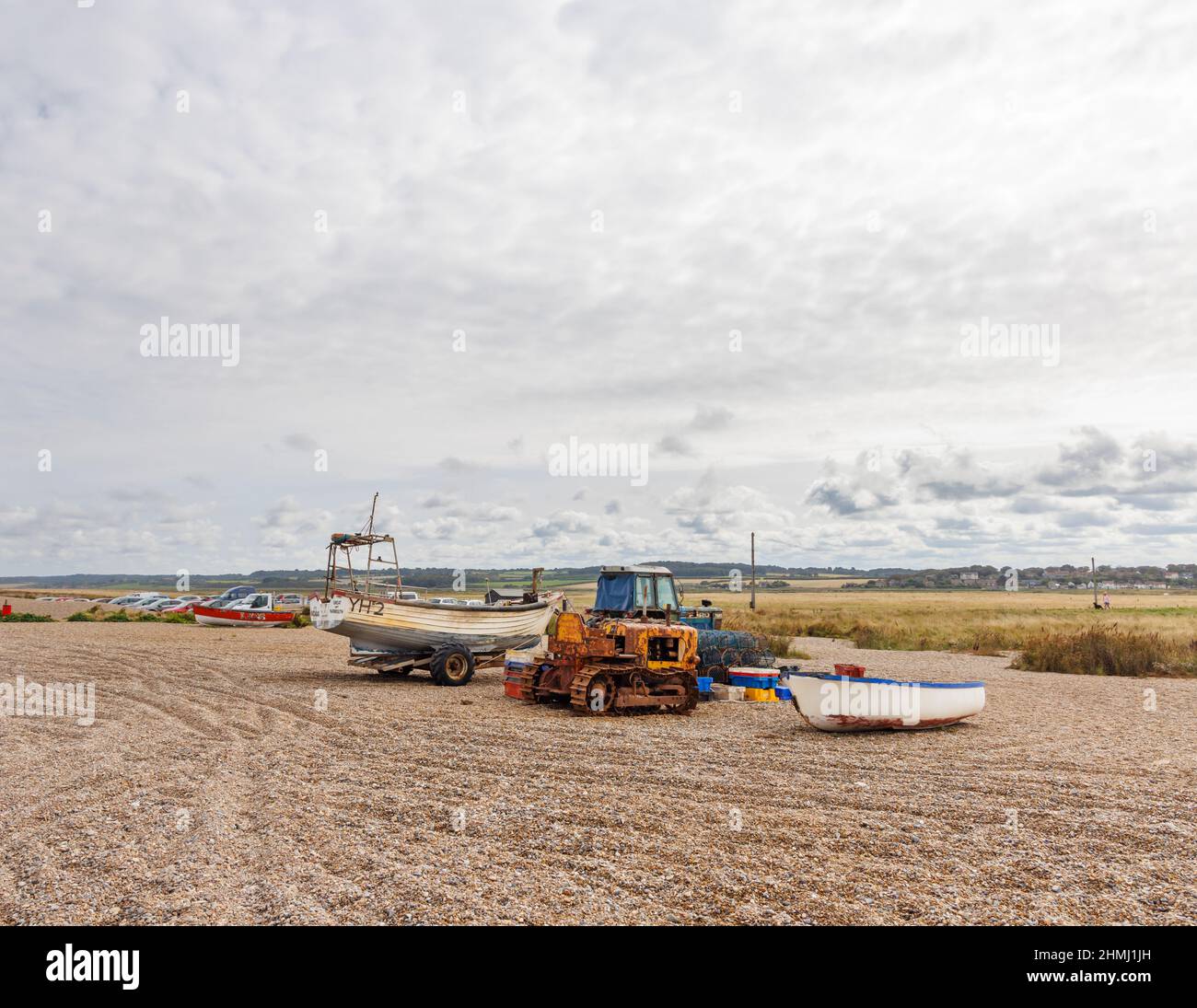 Ein rostiger alter Raupendozer, ein Traktor und ein Fischerboot auf einem Kiesstrand, Cley-Next-the-Sea, einem Dorf im Norden von Norfolk, East Anglia, England Stockfoto
