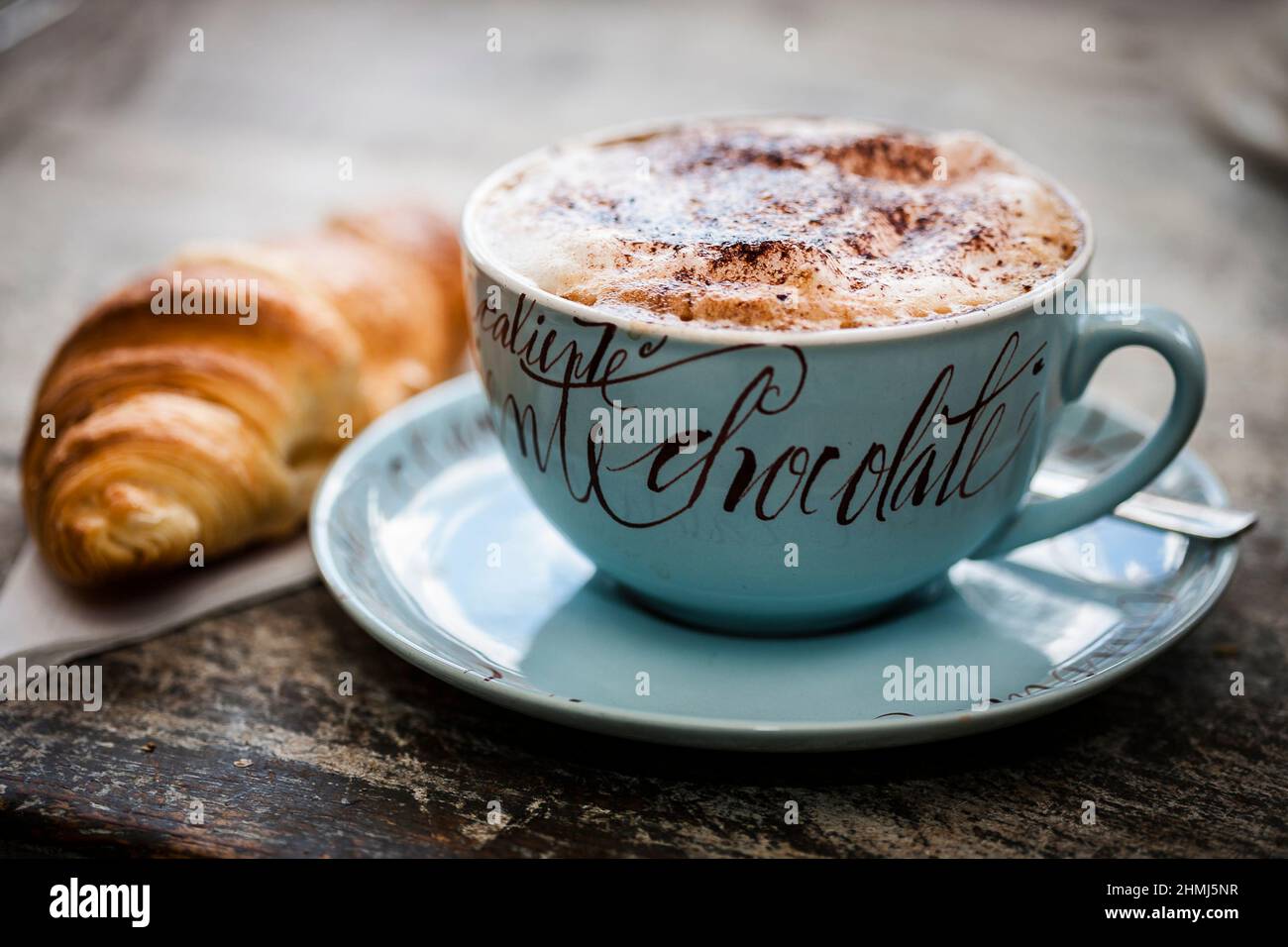 Schaumige Tasse heiße Schokolade mit einer Prise Kakaopulver auf einer rustikalen Holzarbeitsfläche Stockfoto