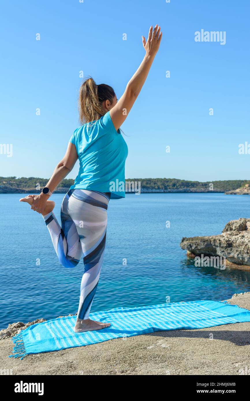 Fitness-Frau mittleren Alters im Freien vor dem Meer macht Yoga-Stretching-Übungen. Stockfoto