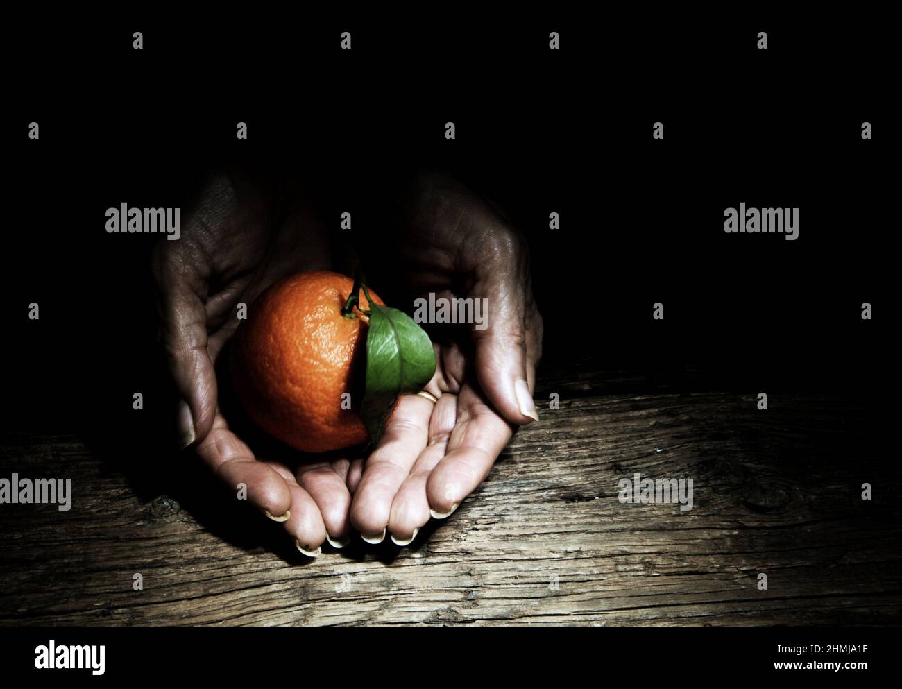 Manderini, composizione di mani e frutta su mase legno Stockfoto