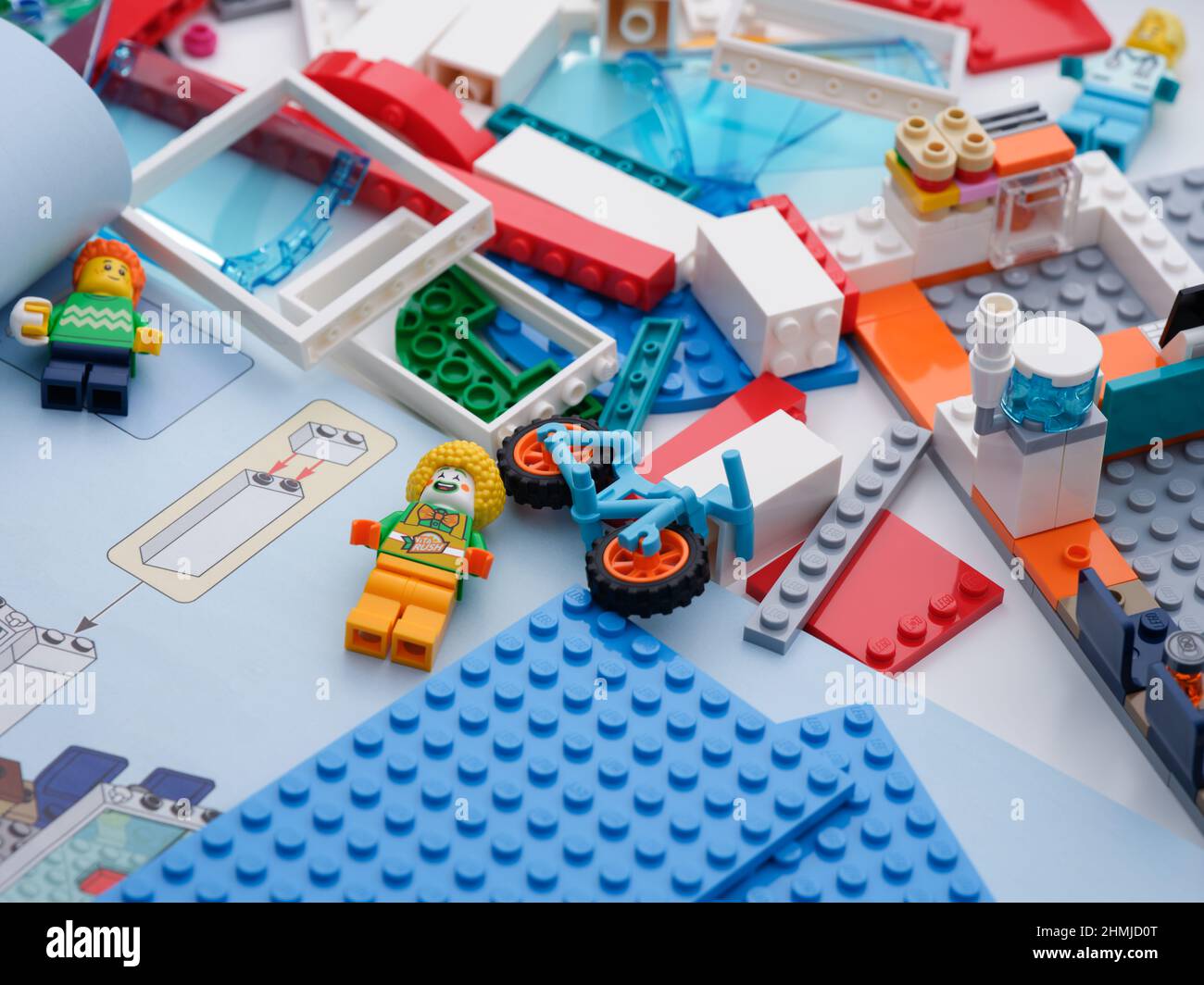 Tambow, Russische Föderation - 09. Februar 2022 einige Lego-Stücke und Minifiguren auf einem Schreibtisch mit einem geöffneten Anleitungsheft in ihrer Nähe. Nahaufnahme. Stockfoto