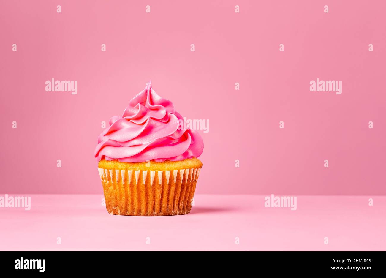 Pink Cupcake mit Buttercreme auf einem rosa Hintergrund. Stockfoto