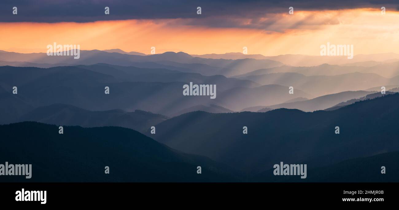 Panorama mit atemberaubendem Sonnenaufgang. Landschaft mit hohen Bergen und Wäldern. Die Sonnenstrahlen leuchten durch den Nebel. Das Spiel von Licht und Schatten. Lokat Stockfoto