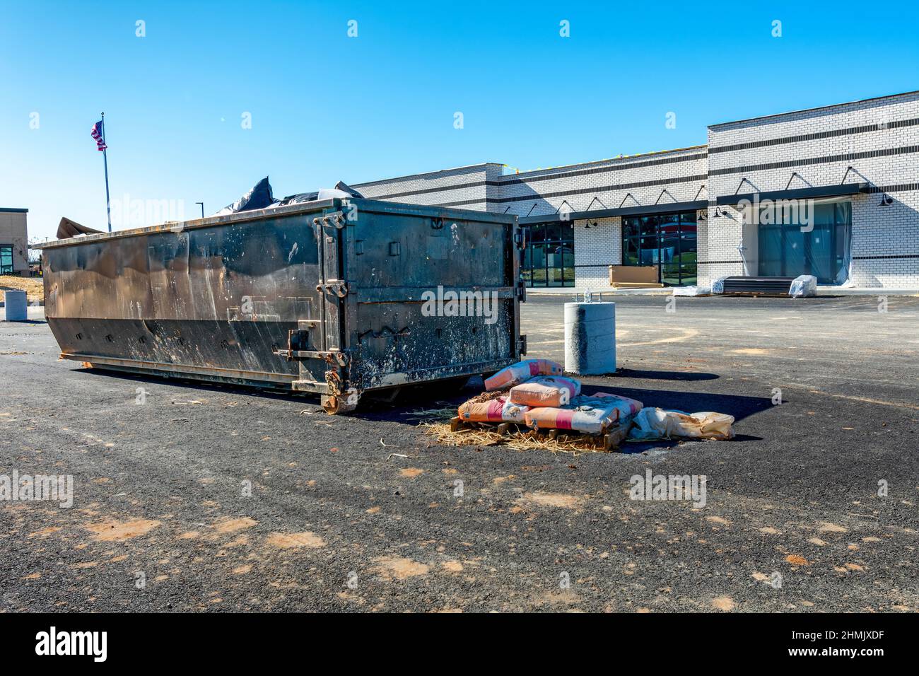 Horizontale Aufnahme eines tragbaren Müllhalters oder Müllwagens vor einer kommerziellen Baustelle. Stockfoto