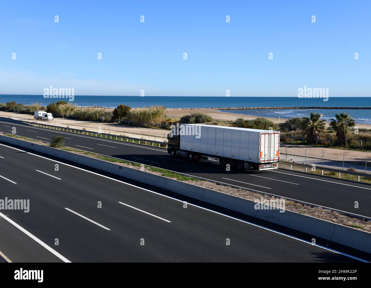 Sattelschlepper fahren entlang der Autobahn. Verkehr auf Autobahn und Straße in Meeresnähe. Logistik des Transports und der Lieferung von Waren. Services und Trans Stockfoto