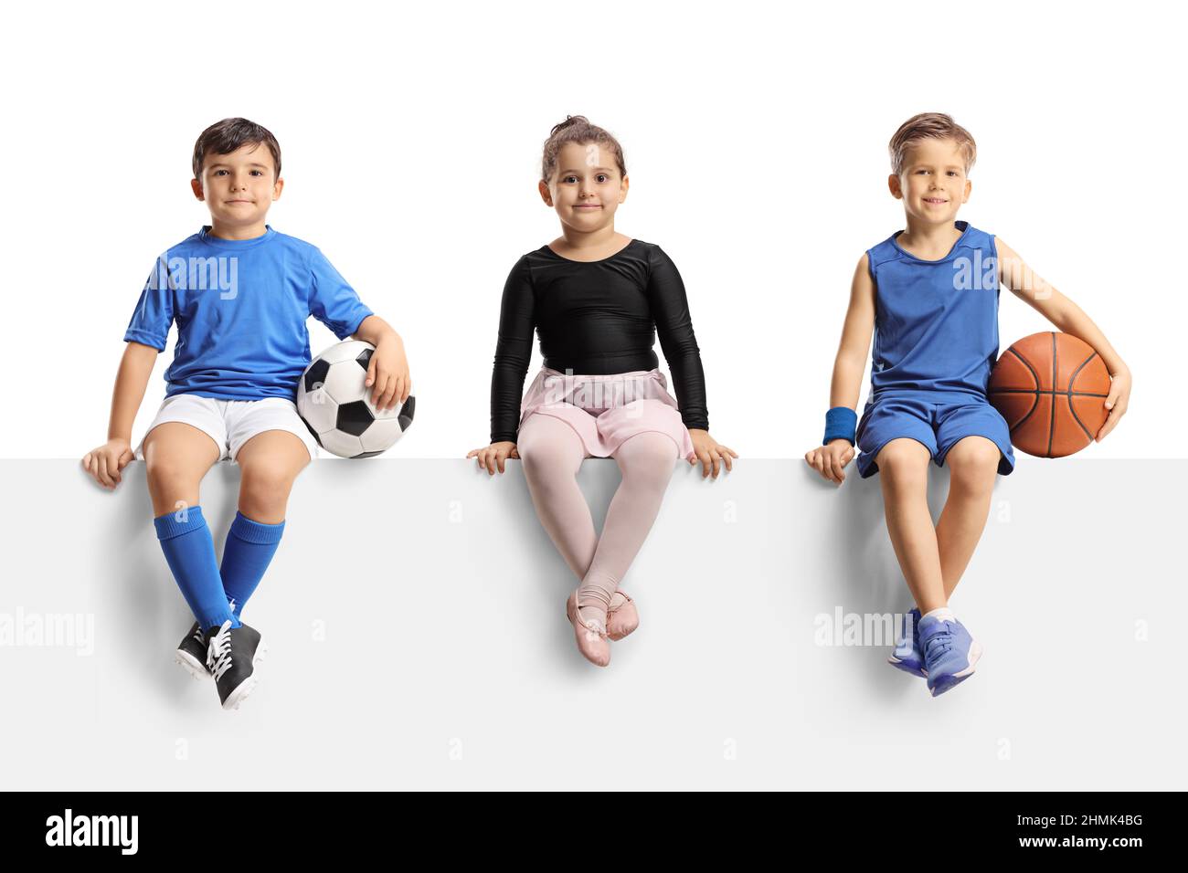 Ballerina Mädchen, Jungen mit Fußball und Basketball sitzen auf einem leeren Panel isoliert auf weißem Hintergrund Stockfoto