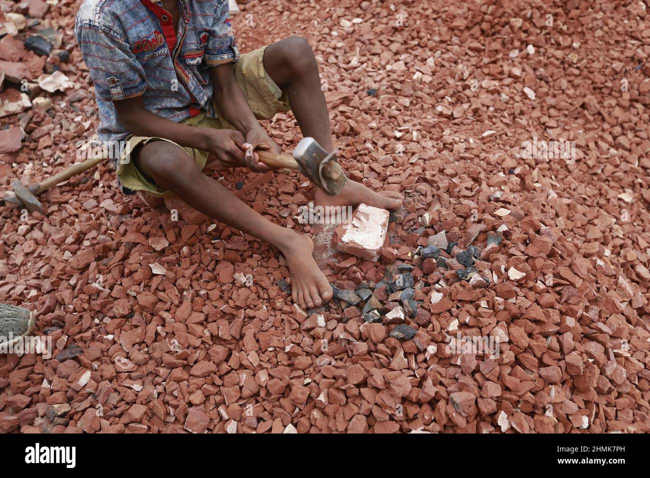 Ramjan, 8, Kinder aus Bangladesch, brechen Ziegel, die als Kies für den Bau in Dhaka, Bangladesch, verwendet werden sollen, 10. Februar 2022. Kinderarbeit ist in Bangladesch üblich, 4,7 Millionen Kinder im Alter von 5 bis 14 Jahren arbeiten in der Belegschaft. Von den Kinderarbeitern, die in der Belegschaft beschäftigt sind, sind 83 % in ländlichen Gebieten und 17 % in städtischen Gebieten beschäftigt. Im Jahr 2006 verabschiedete Bangladesch ein Arbeitsgesetz, in dem das Mindestalter für eine Beschäftigung auf 14 Jahre festgelegt wurde. Dennoch ist die Durchsetzung solcher Arbeitsgesetze in Bangladesch praktisch unmöglich, da 93 % der Kinderarbeiter im informellen Sektor wie Smal beschäftigt sind Stockfoto