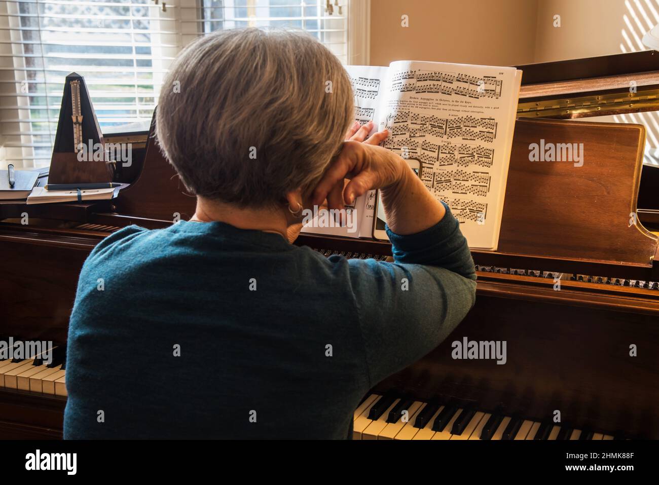 Südjordanien, Utah, USA. Februar 10, 2022. Ein Klavierlehrer verwendet ein Smartphone und facetime, um einen virtuellen Klavierunterricht zu erteilen. Ein schwieriger Prozess. Stockfoto