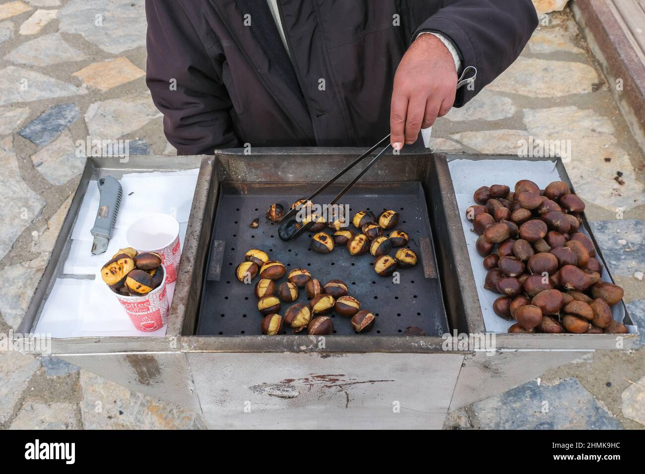 Man Hand verkauft traditionelle Kastanien auf einer Straße, frisch gekochte Kastanien von turkısh Cuisine, Street Market, türkische Küche und Kochkonzept. Stockfoto