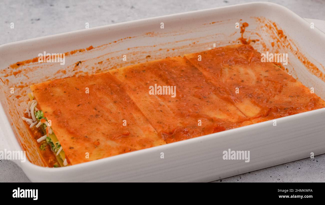 Lasagne zusammenbauen. Die letzte Lasagne mit Marinara-Sauce überziehen. Rezept für Spinat-Lasagne Stockfoto
