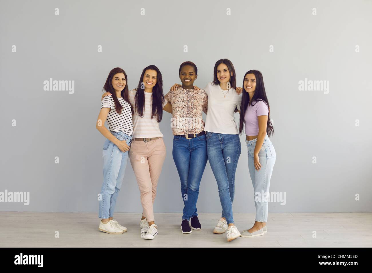 Porträt selbstbewusster multirassischer Freundinnen in legerer Kleidung, die in Innenräumen in der Nähe der Wand stehen. Stockfoto