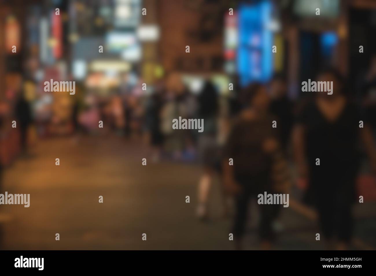 Verschwommener abstrakter Hintergrund von Menschen, die nachts auf der Straße spazieren Stockfoto