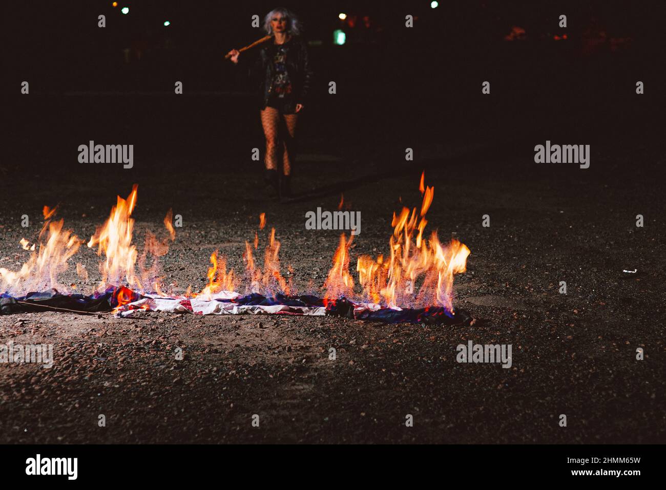 Porträt einer stilvollen blonden grunge junge Frau mit dem Club in der Nähe des Feuers Stockfoto