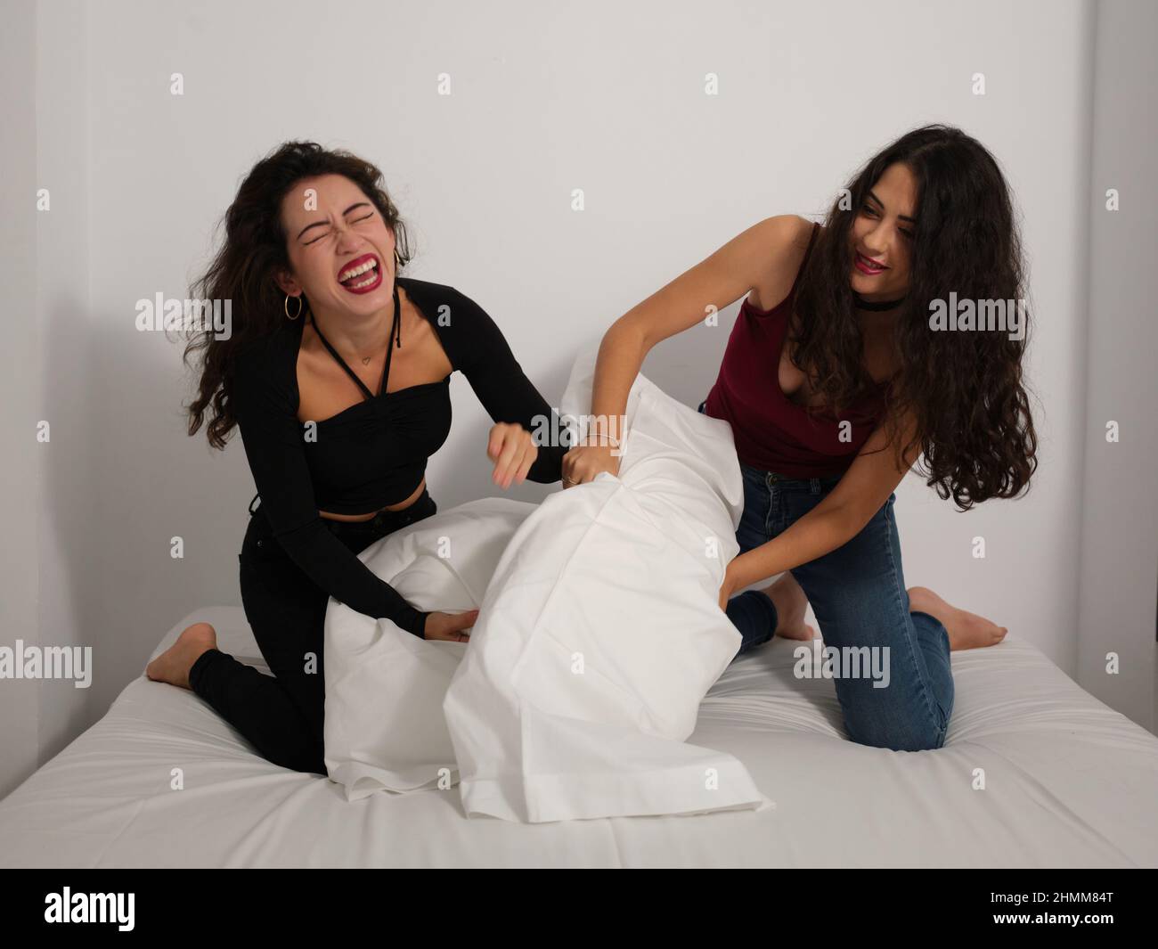 Zwei Mädchen haben Spaß und lachen beim Kissenkampf im Bett. Stockfoto