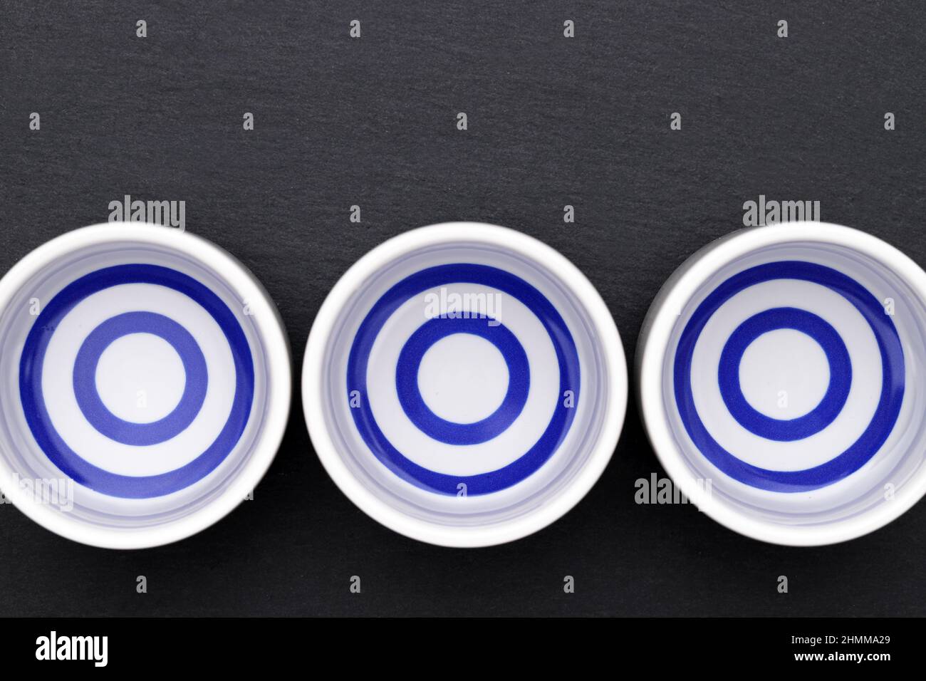 Japanischer Sake in traditioneller Keramik-Ochoko-Tasse auf schwarzem Hintergrund Stockfoto