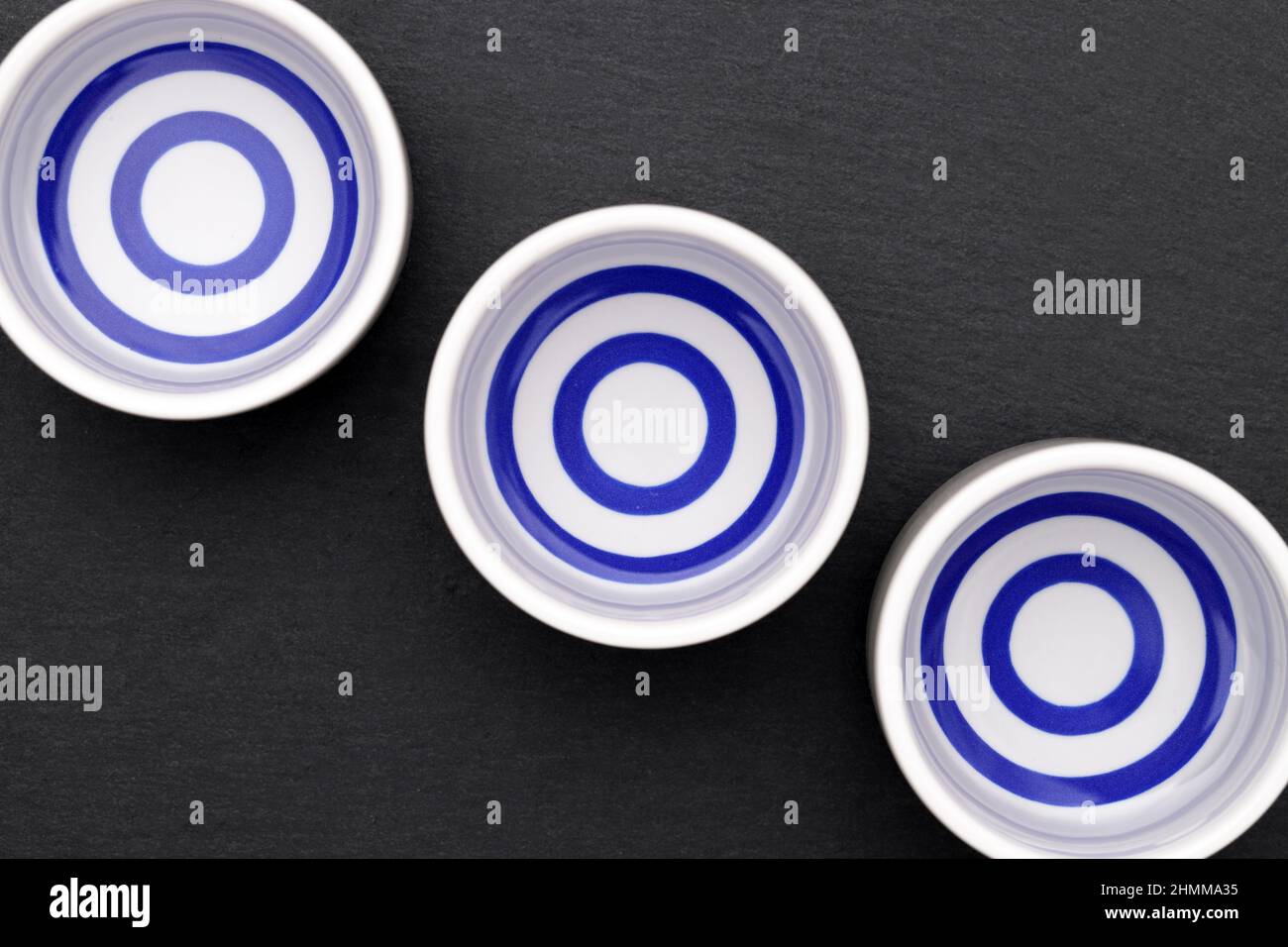 Japanischer Sake in traditioneller Keramik-Ochoko-Tasse auf schwarzem Hintergrund Stockfoto